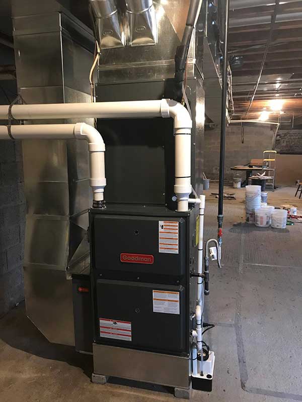 Heat Pump in basement with two large angled pipes and ductwork.